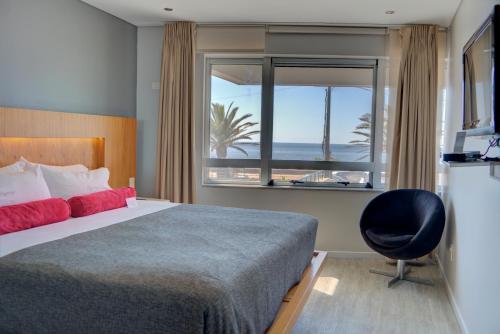 1 dormitorio con cama, ventana y silla en Regency Rambla Design Apart Hotel en Montevideo