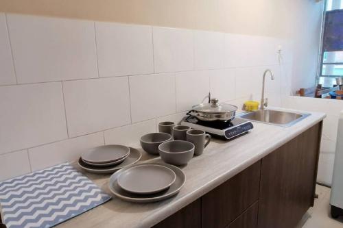 a kitchen counter with plates and pans and a sink at Comfort home 5min to Airport 15min to city center 近机场 适合小家庭 安静小区 in Penampang