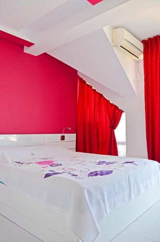 a red bedroom with a white bed and a red curtain at Akra Apartments in Chernomorets