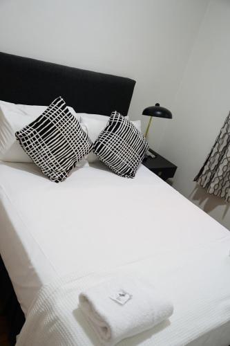 a bed with two black and white pillows on it at The Tamworth Hotel in Tamworth
