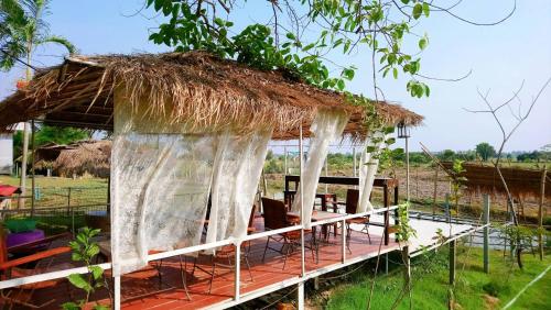 a hut with a thatched roof in a field at Raina-Suanpa Lung Sood Farmstay in Suphan Buri