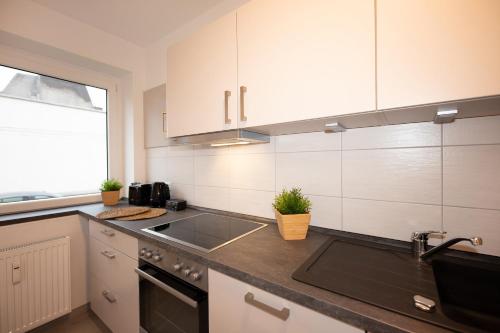 a kitchen with white cabinets and a sink at FeWo Batteriestraße in Bremerhaven