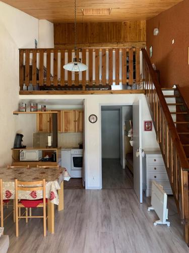 uma cozinha e sala de jantar com uma mesa e uma escada em RESIDENCE UBAYE A 23 em Le Sauze