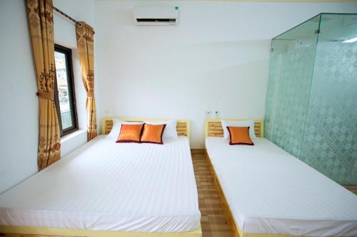 2 Betten mit orangefarbenen Kissen in einem Zimmer in der Unterkunft Tràng an Bái đính Linh homestay Ninh bình in Ninh Bình