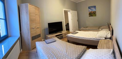a small room with two beds and a television at Apartament Aleksandra in Gniezno