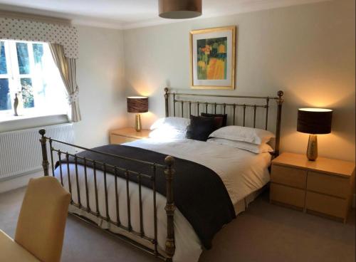 a bedroom with a bed with two lamps and a window at Keepers Lodge in Swithland