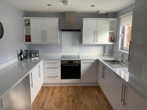 a white kitchen with white cabinets and a sink at Flat One, 212 Eaglesham Road, East Kilbride, Glasgow in Glasgow