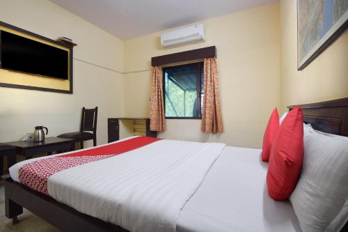 a bedroom with a bed with red pillows and a window at OYO 24408 Nirmala Guest House in Jodhpur