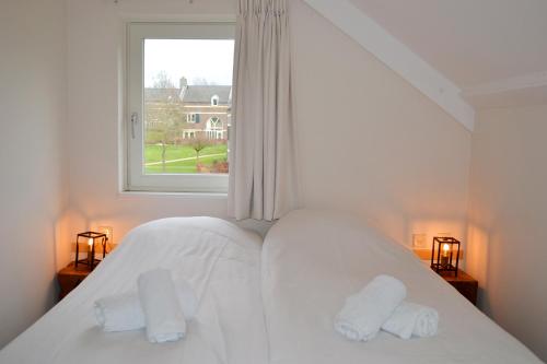 a bedroom with a bed with white sheets and a window at Buitenplaats De Mechelerhof in Mechelen