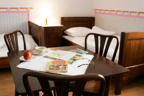 un tavolo con sedie con un libro e una mela sopra di Dom gościnny w Bartniku a StrÃ³Å¼e