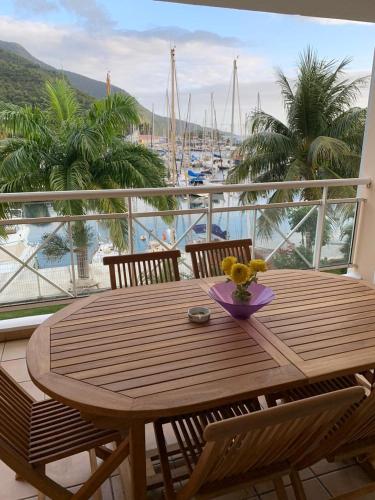 a wooden table and chairs on a balcony with a marina at logement entier vue sur mer in Gourbeyre