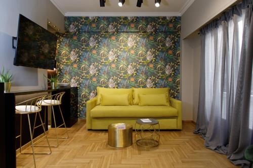 a yellow couch in a living room with a floral wall at Soho Apartments in Athens