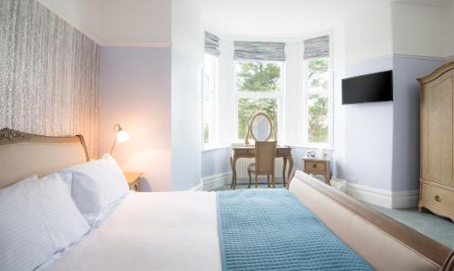 a bedroom with a bed and a desk with a mirror at Gwesty Gadlys Hotel in Cemaes Bay
