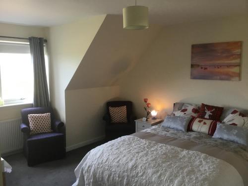 a bedroom with a bed and two chairs at Rhenetra in Arisaig