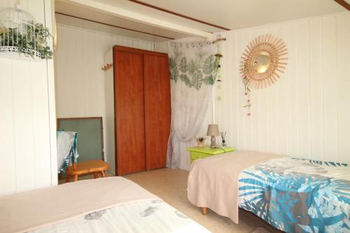 une chambre avec deux lits et un miroir au mur dans l'établissement Domaine de vacances à 600m de la plage villa climatisée, 2 chambres, 4 à 6 couchages WIFI, terrasse angle, parking, animations et piscines en supplément LRTAMG1, à Portiragnes