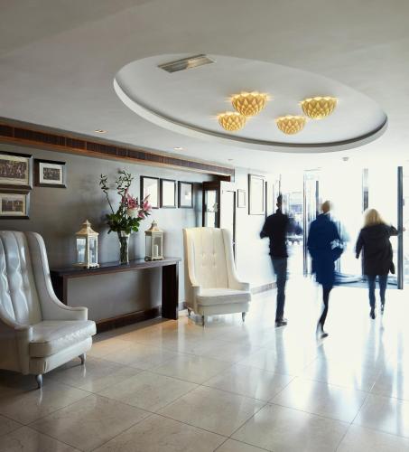 two people walking in a lobby with two chairs at Killarney Towers Hotel & Leisure Centre in Killarney