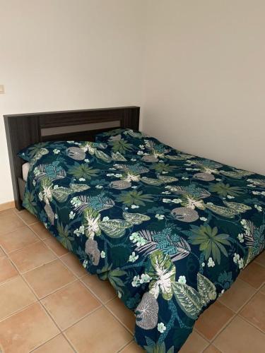 a bed with a blue blanket with plants on it at logement entier vue sur mer in Gourbeyre