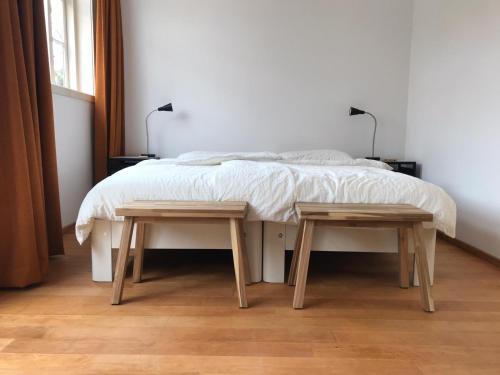 a bedroom with a bed and two wooden tables at Huis nummer 1 in Eindhoven