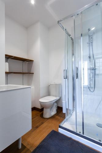 une salle de bain avec toilettes et douche en verre dans l'établissement La maison des couturières, à Cluny