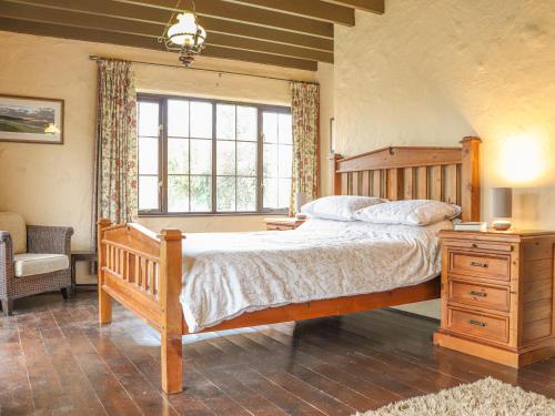 a bedroom with a wooden bed and a window at Stoney Cottage in Narberth