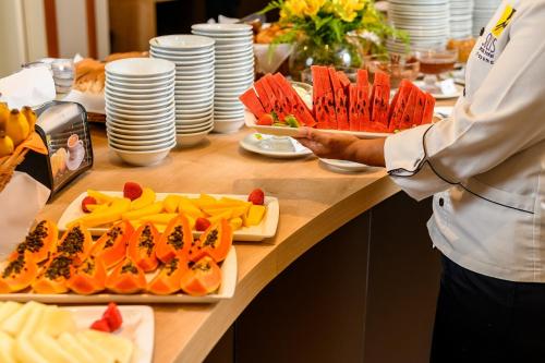 a person standing in front of a buffet with food at Solis Praia Hotel Itapema in Itapema
