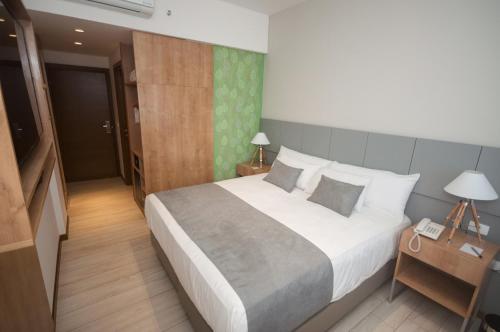 a bedroom with a large bed and a night stand with a telephone at Dazzler by Wyndham Ciudad del Este in Ciudad del Este