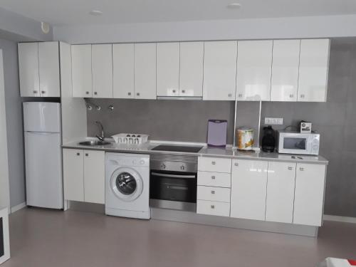 uma cozinha com armários brancos e uma máquina de lavar roupa em Apartamentos Centro em Santa Pola