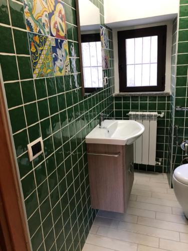 Baño de azulejos verdes con lavabo y aseo en Ka suporti en Civita