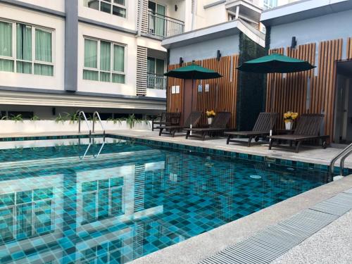 a swimming pool with chairs and umbrellas next to a building at Asoke Bts Mrt Bangkok New Luxury Room in Bangkok