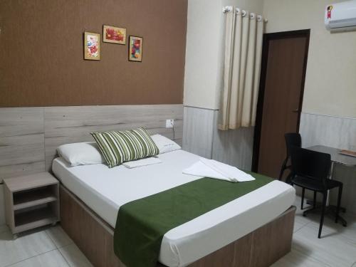 a bedroom with a bed with a desk and a chair at Hotel Uzi Mar in Recife