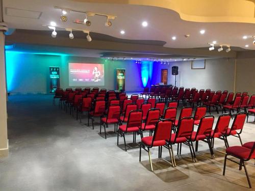 a conference room with red chairs and a screen at Meu Hotel Boituva in Boituva