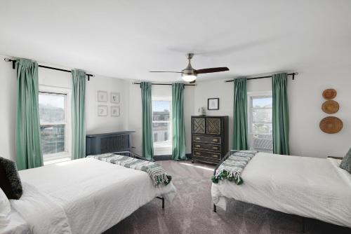 two beds in a room with green curtains and windows at Modern Parisian Apartment in the Heart of Manayunk in Philadelphia