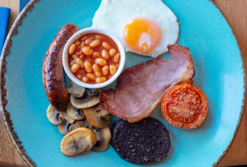 a blue plate of breakfast food with eggs sausage beans and mushrooms at Gwesty Gadlys Hotel in Cemaes Bay