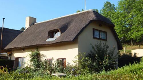 una casa con tetto di paglia e tetto di paglia. di Manwood Lodge a Henburg Park