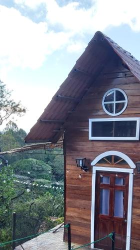 a small wooden house with a red door at Hotel Monte Campana Heredia in Birrí