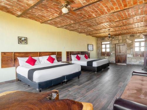 a hotel room with two beds and a couch at Capital O Hotel Posada Terraza, Tequila Jalisco in Tequila