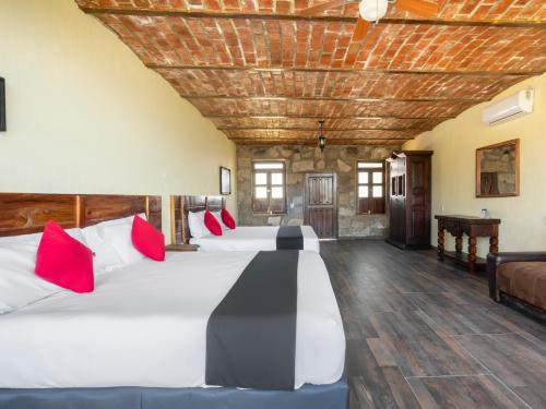 a large room with four beds with red pillows at Capital O Hotel Posada Terraza, Tequila Jalisco in Tequila