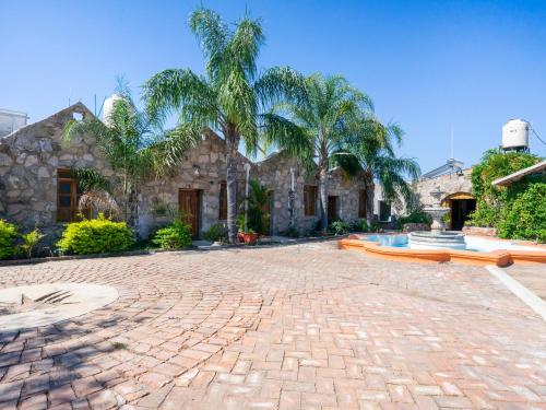 a brick courtyard with palm trees and a building at Capital O Hotel Posada Terraza, Tequila Jalisco in Tequila