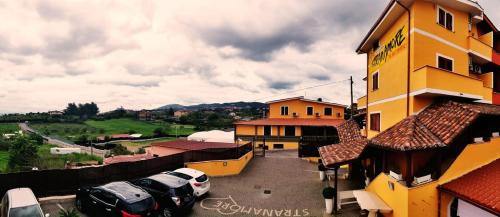 a yellow building with cars parked in a parking lot at Affittacamere Stranamore in Frascati