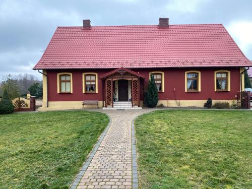 a red house with a red roof on a grass field at Agro na Wapniarni in Białla