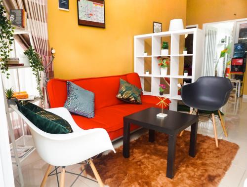 a living room with a red couch and two chairs at Tropical Boutique Batu Villa, Near Museum Angkut in Batu