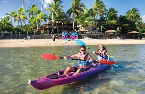 two women in a purple kayak on the beach at Outrigger Fiji Beach Resort in Korotogo