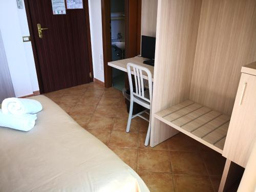 a small room with a bed and a desk with a computer at Casa Betania in Pisa