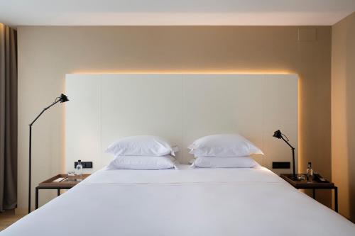 a large white bed with two pillows on it at Casa Elliot Hotel in Barcelona