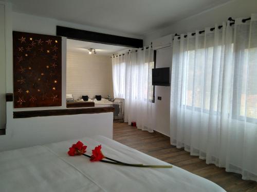 a bedroom with a white bed with red flowers on it at Hotel Sierra Madrona in Fuencaliente