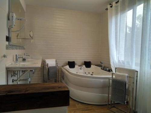Baño blanco con bañera y lavamanos en Hotel Sierra Madrona, en Fuencaliente