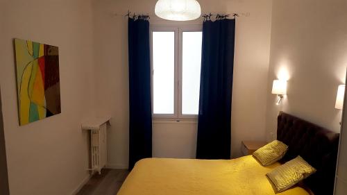 a bedroom with a yellow bed and a window at Le LAZARET in Marseille