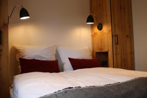 una camera con un letto bianco con due cuscini rossi di Mountain Suite a Brienz