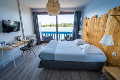 a hotel room with a bed and a desk and a window at Le Relais Du Lac in Hossegor