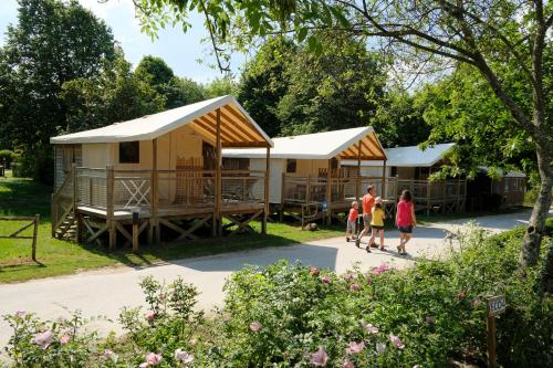 a group of people walking past two yurt buildings at Camping Capfun La Bretèche in Les Épesses